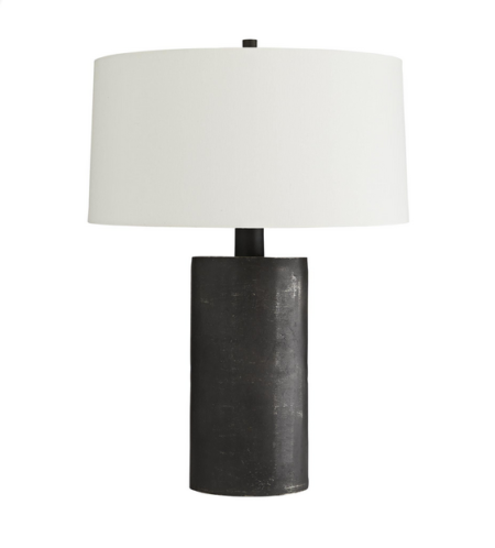 Profis Lamp Dark and mysterious, this table lamp brings light even with its own inky hue. It’s completely crafted from blackened aluminum, one of our first pieces to adorn this rich finish. The result is a sort of matte graphite look, with a bit of a raw effect, which brings out the industrial edge of this lamp. It is topped with an off-white linen drum shade with white cotton lining. H: 29.5IN Dia: 22.00IN